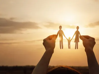 Child holding paper cut-outs of a fmaily in the sunlight